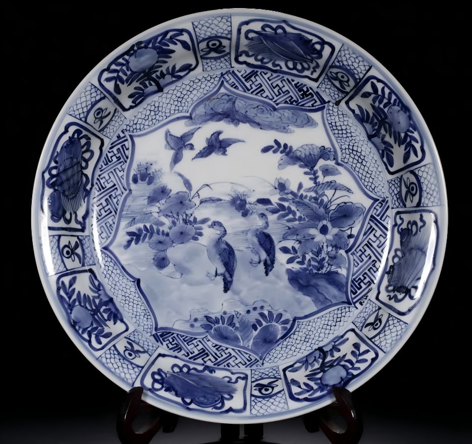 A Qing Dynasty blue and white flower and bird pattern plate: This plate is dignified, elegant and elegant, with an open mouth, folded edges, curved belly, and circle feet. The glaze is smooth and shiny. Decorated with blue and white, painted with flower and bir