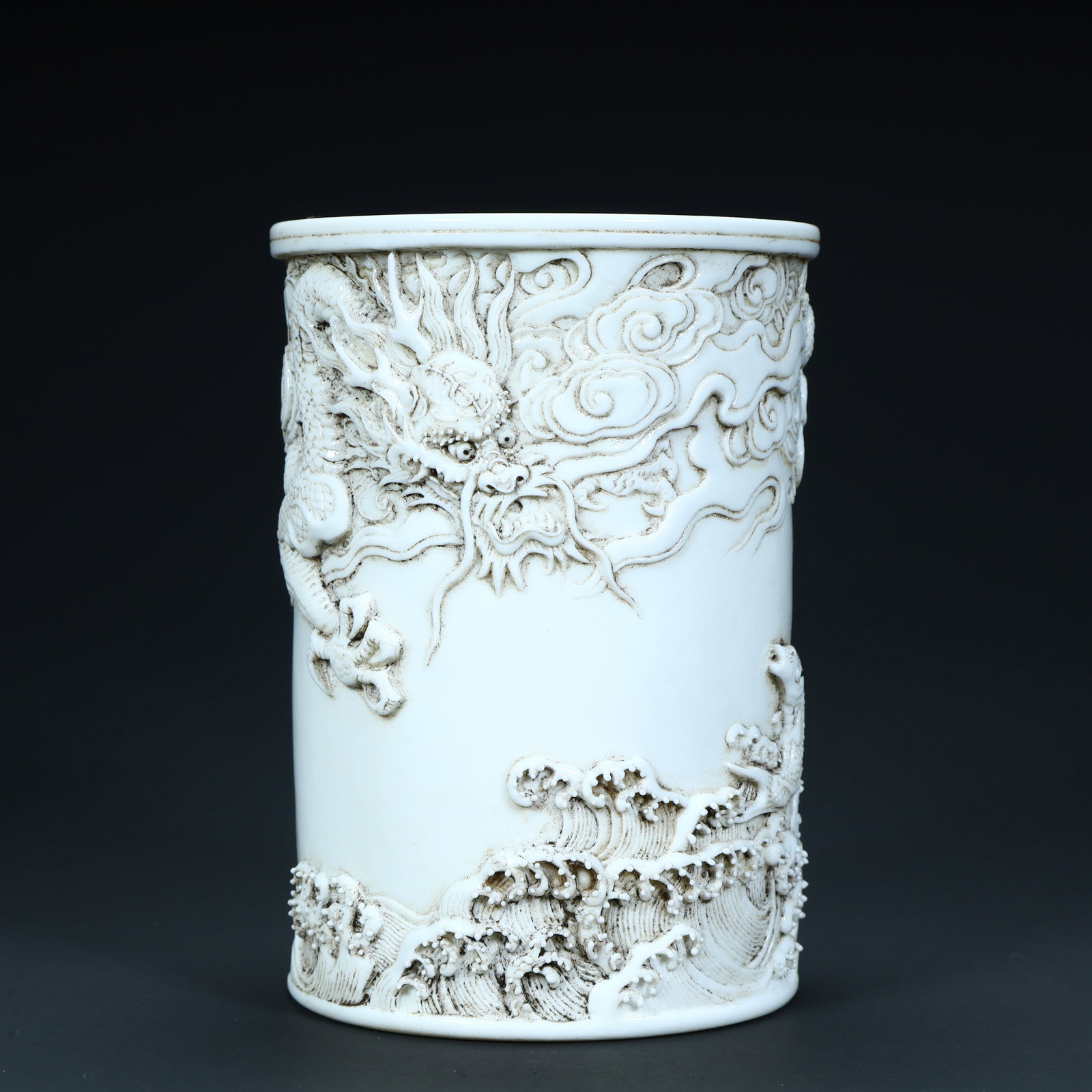 A fine late Qing dynasty white-glazed carved porcelain brush pot with cloud and dragon motifs: A late Qing dynasty white-glazed carved porcelain brush pot with cloud and dragon motifsSIZE:H: 11.5cm L: 8cm W: 8cm W: 491g(The Dimensions Of All Batches Are Manually Measured.If You Need More Detail