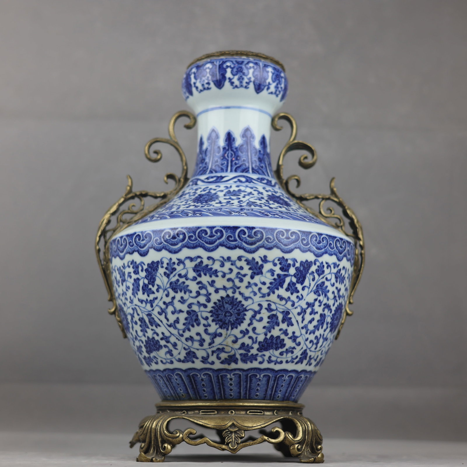 A fine Qing Dynasty blue-and-white lotus pattern with gilded copper scroll leaf garlic handles: Qing Dynasty blue-and-white lotus pattern with gilded copper leaf and garlic head vase with entwined lotus leavesSIZE: H:41.5cm D:10.5cm D:26cm Base diameter: 19cm(The Dimensions Of All Batches Are Ma