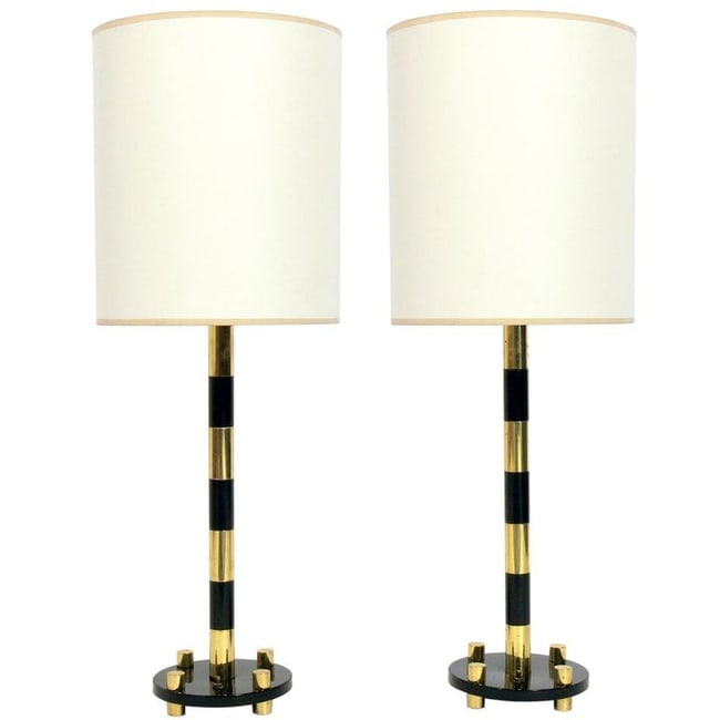 Pair of Tommi Parzinger Style Lamps: Elegant brass and black lamps, in the manner of Tommi Parzinger, American, circa 1950s. The shades are NOT included. They measure 28.5"H to the tops of the harps x 7" diameter.
