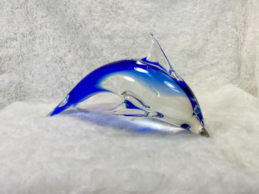 Murano Style Art Glass Dolphin — Blue & Clear Art Glass Sculpture: This exquisite art glass dolphin sculpture showcases a mesmerizing blend of rich cobalt blue and crystal-clear glass, expertly crafted through the hand-blowing technique. The sleek, fluid design captu