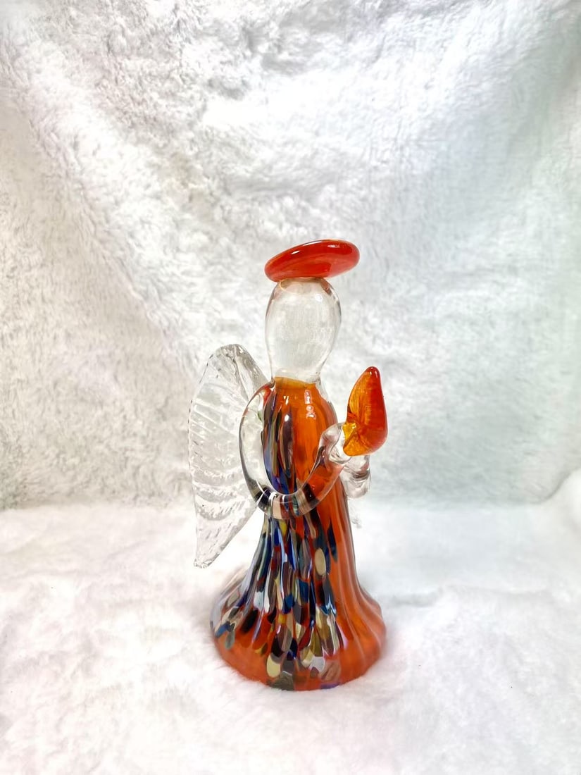 Handblown Art Glass Angel – Orange & Multicolor Murano Style Art Glass: This captivating art glass angel sculpture features a striking combination of orange, red, and speckled multicolors. The figure is adorned with textured, clear glass wings and a bold orange halo, hold