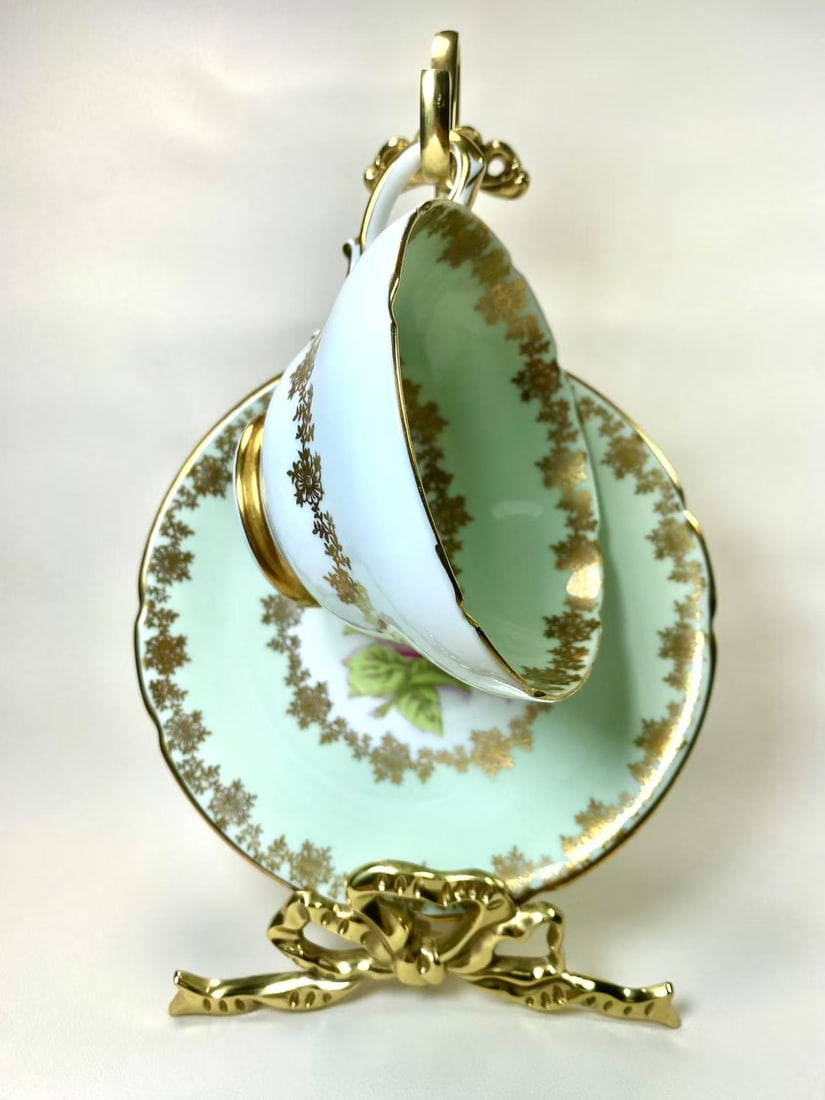 Stanley Fine Bone China Rose & Gold Tea Cup and Saucer Set - Est. 1875: This exquisite fine bone china tea cup and saucer set by Stanley features a charming mint green base adorned with a hand-painted rose motif and delicate gold floral patterns. The edges are elegantly g