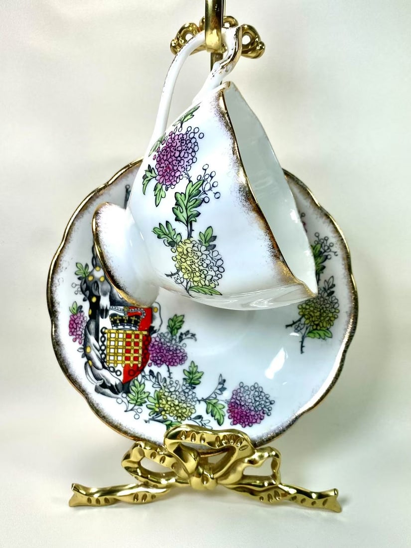 Queen Anne Fine Bone China "Queen’s Beasts" Crest Series Tea Cup and Saucer Set - The Beaufort: This exquisite fine bone china tea cup and saucer set by Queen Anne is part of the "Queen’s Beasts" collection, featuring the iconic Beaufort Shield crest design. Detailed floral patterns frame the