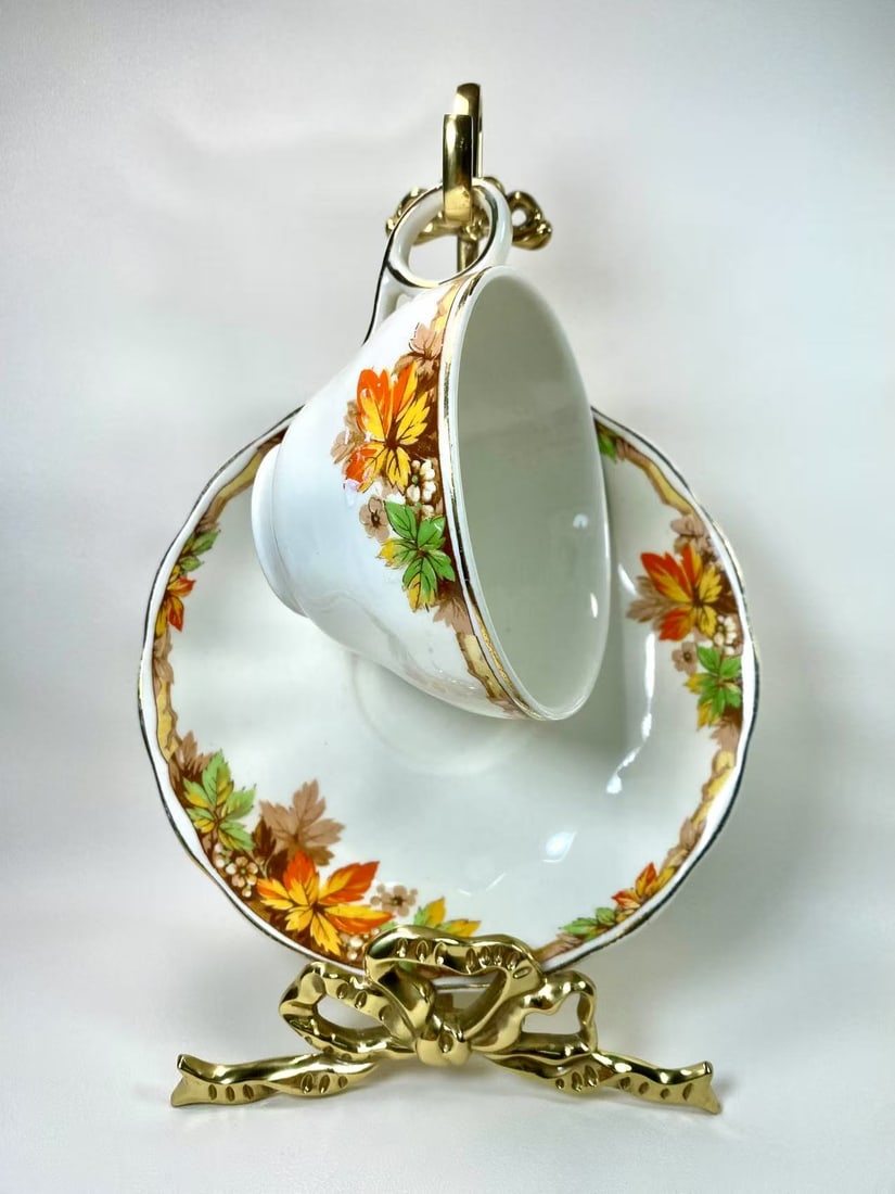 Grindley England Cream Petal Autumn Leaves Tea Cup and Saucer Set: This charming tea cup and saucer set from Grindley England's Cream Petal series features vibrant autumn leaves and berry patterns with gold-trimmed edges. A classic collectible piece that brings the w