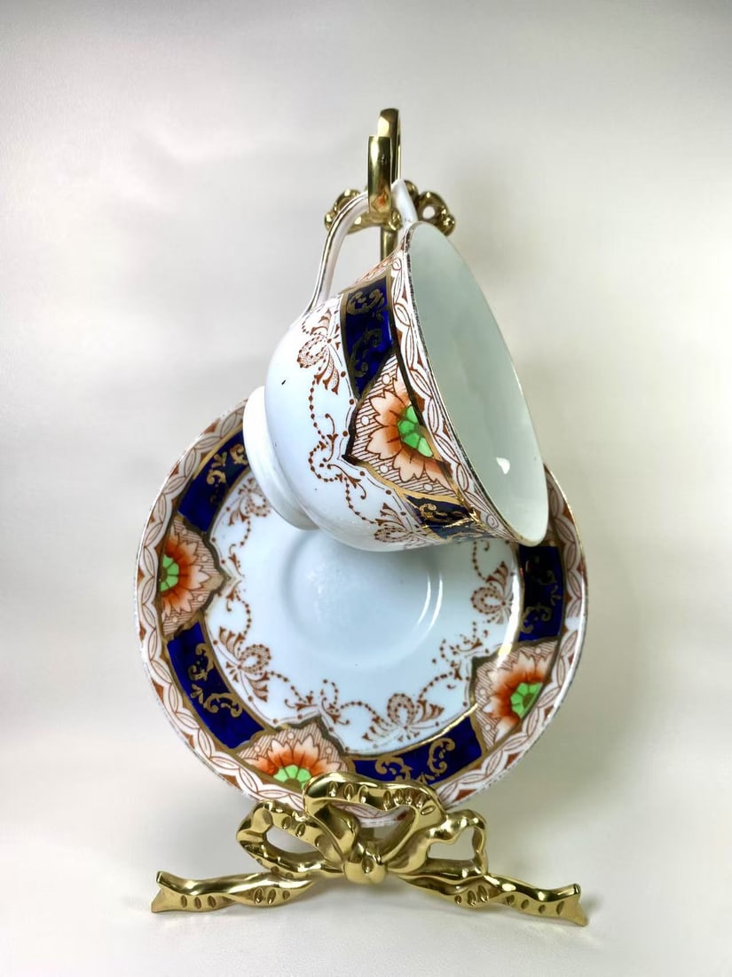 Royal Osborne England Blue and Gold Floral Tea Cup and Saucer Set: A captivating tea cup and saucer set by Royal Osborne England, adorned with intricate floral patterns in vibrant blue, gold, and peach tones. This elegant duo exudes timeless sophistication, perfect f