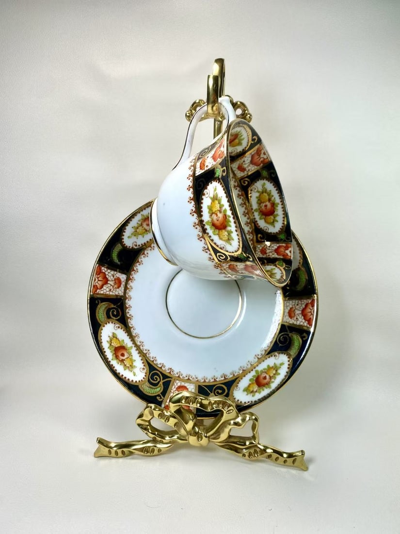 Superior England Imari Style Black and Gold Tea Cup and Saucer Set: A captivating tea cup and saucer set by Royal Osborne England, adorned with intricate floral patterns in vibrant blue, gold, and peach tones. This elegant duo exudes timeless sophistication, perfect f