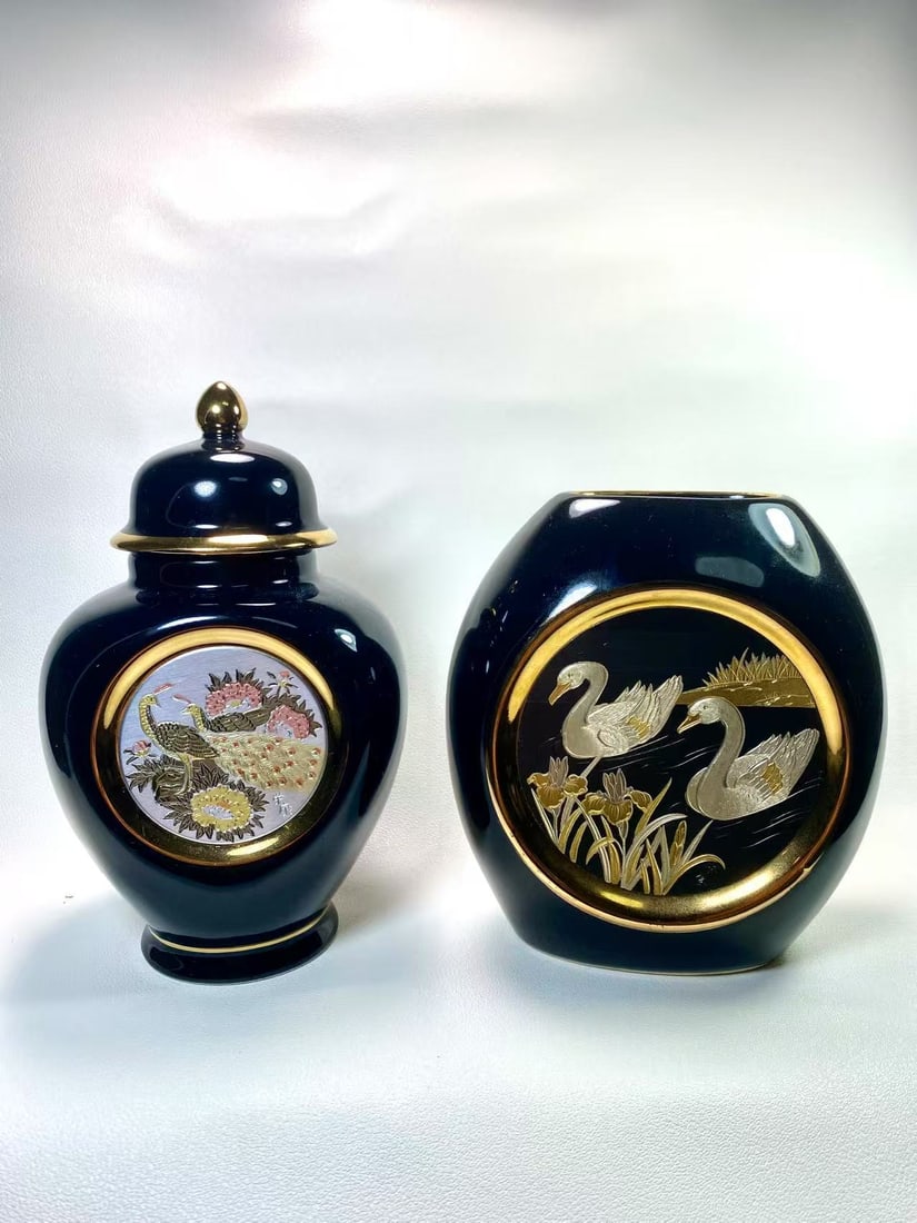 Japanese Chokin Gilded Vase and Lidded Jar Set – Black with 24K Gold Trim: This exquisite set of Japanese Chokin art pieces includes a lidded jar featuring floral and peacock motifs and a vase adorned with graceful swans, both framed in 24K gold and set against a striking bl