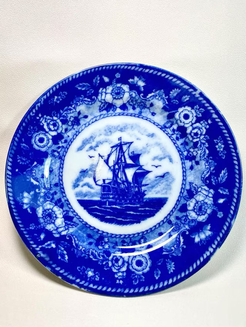 Japanese Blue Flower Transferware Plate with Sailing Ship Scene: This vintage transferware plate was made in Japan under the brand “Blue Flower,” featuring a striking sailing ship motif at its center, surrounded by intricate floral and rope patterns. Render