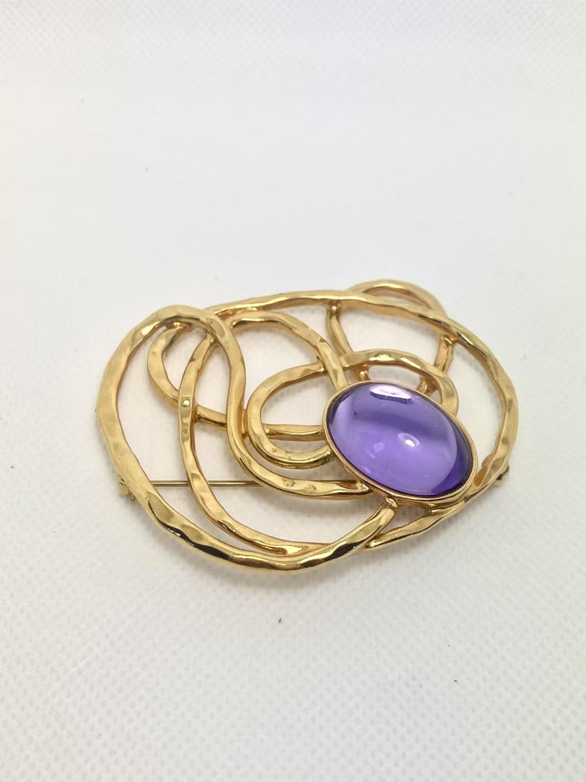 Vintage Avon Abstract Gold Tone Brooch with Purple Cabochon: This eye-catching Avon brooch features an abstract openwork gold tone design with a central purple cabochon. Bold yet elegant, ideal for collectors or vintage outfit accents.