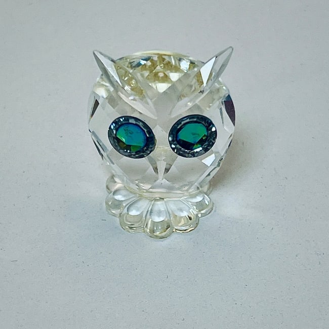 Crystal Owl Figurine | Green-Blue Gemstone Eyes: This charming crystal owl figurine is crafted with brilliant faceted detailing and features a flower-shaped base. The owl's large eyes are adorned with stunning green-blue gemstone accents, reflecting