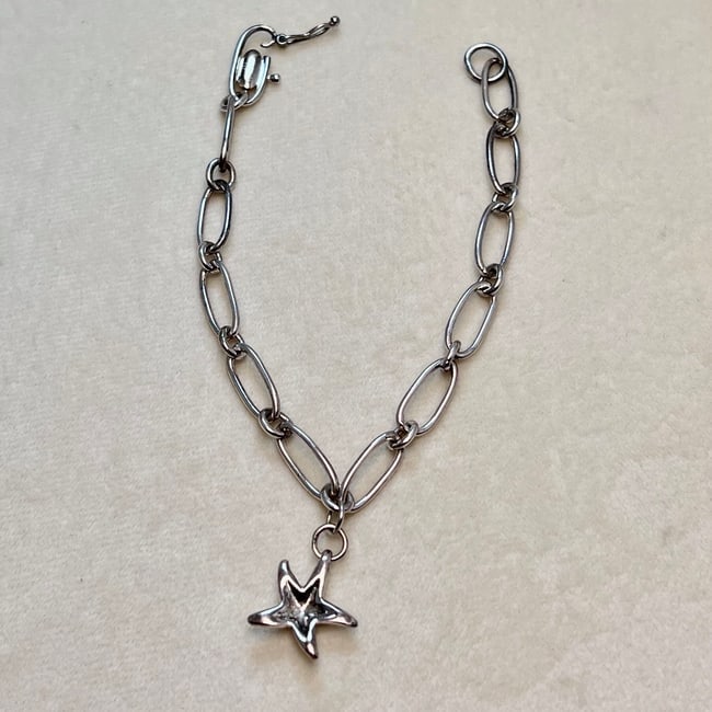 Silver Starfish Charm Bracelet – Marked Tiffany & Co. Elsa Peretti: A silver charm bracelet featuring a stylized starfish pendant, marked “Tiffany & Co. 925” and signed “Elsa Peretti Spain.” The piece shows Peretti’s signature organic design style an