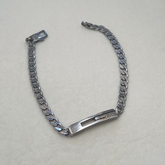 Gucci Sterling Silver 925 Chain Bracelet: This vintage Gucci bracelet is crafted in sterling silver (marked AG 925), featuring a sleek curb chain and an iconic ID plate design with an open slot. The ID bar is engraved with “GUCCI made in It
