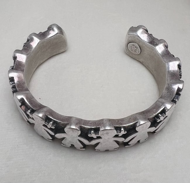 Vintage TOUS Sterling Silver Open Cuff Bracelet with Paper Doll Motif: A bold and playful open cuff bracelet by TOUS, crafted in solid sterling silver and featuring the iconic paper doll silhouette—alternating girls and boys holding hands in a continuous band. The oute