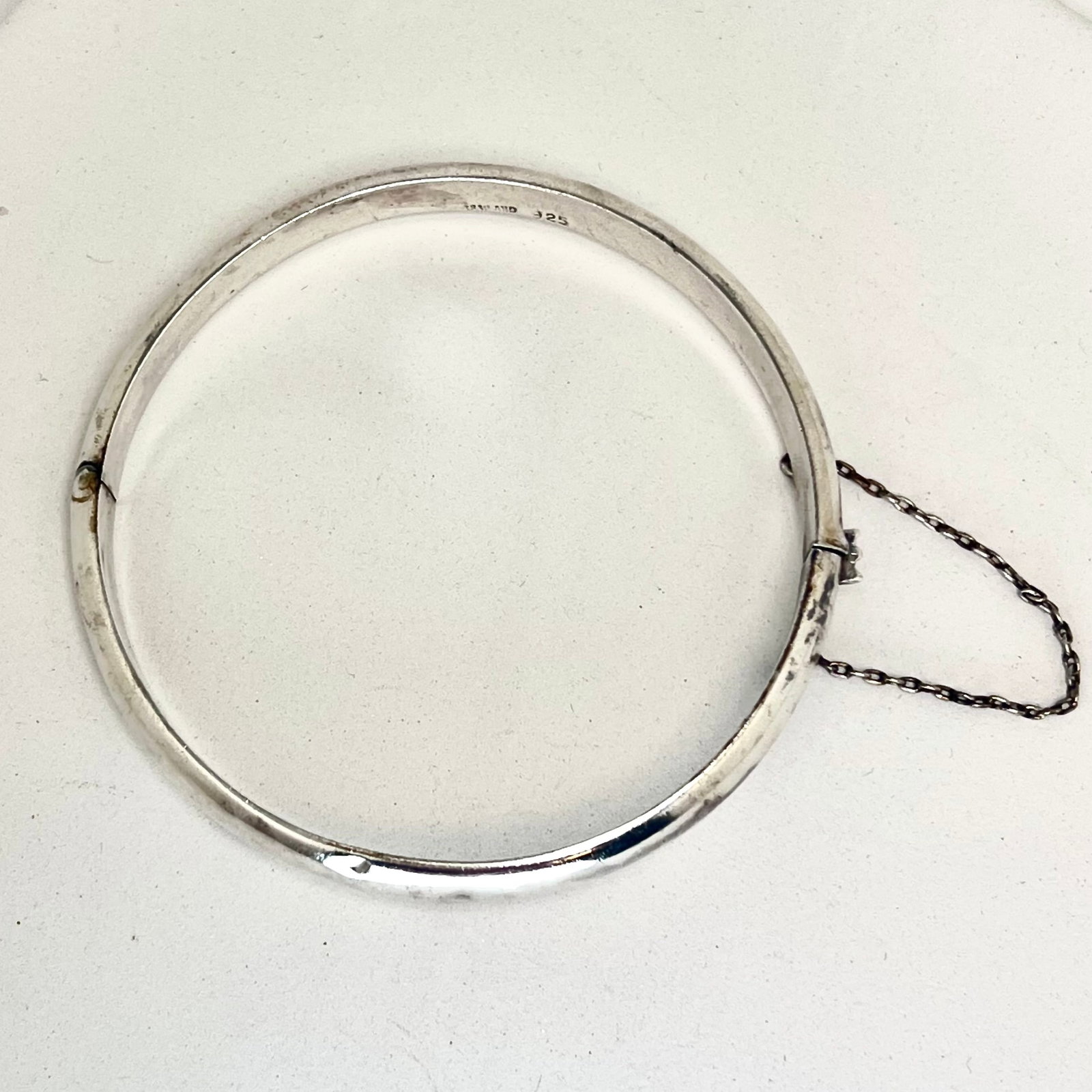 Vintage Sterling Silver Bangle with Safety Chain: This vintage hinged bangle is crafted from solid sterling silver and marked "THAILAND 925" on the inner band. It features a sleek, minimalist design with a secure clasp and original safety chain, offe