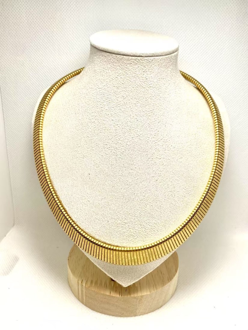 Gold-Tone Herringbone Necklace: Wide gold-tone herringbone necklace with glossy shine and smooth lines. A retro yet trendy choker-style piece that adds a striking touch to any outfit.
