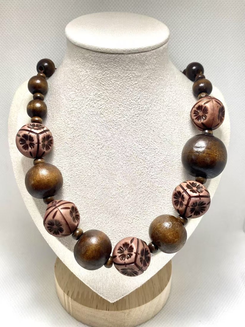 Vintage Brown Carved Wooden Bead Necklace: This necklace features brown wooden beads in various sizes, alternated with carved geometric wooden beads with floral patterns. The rich brown tones and delicate carvings create a natural and vintage 