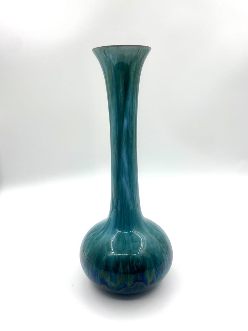 Blue Mountain Pottery Tall Neck Vase, Canada: Crafted by the renowned Blue Mountain Pottery of Ontario, Canada, this tall-neck vase features the brand’s signature flowing blue-green glaze. The vase’s bulbous base gently tapers into an elongat