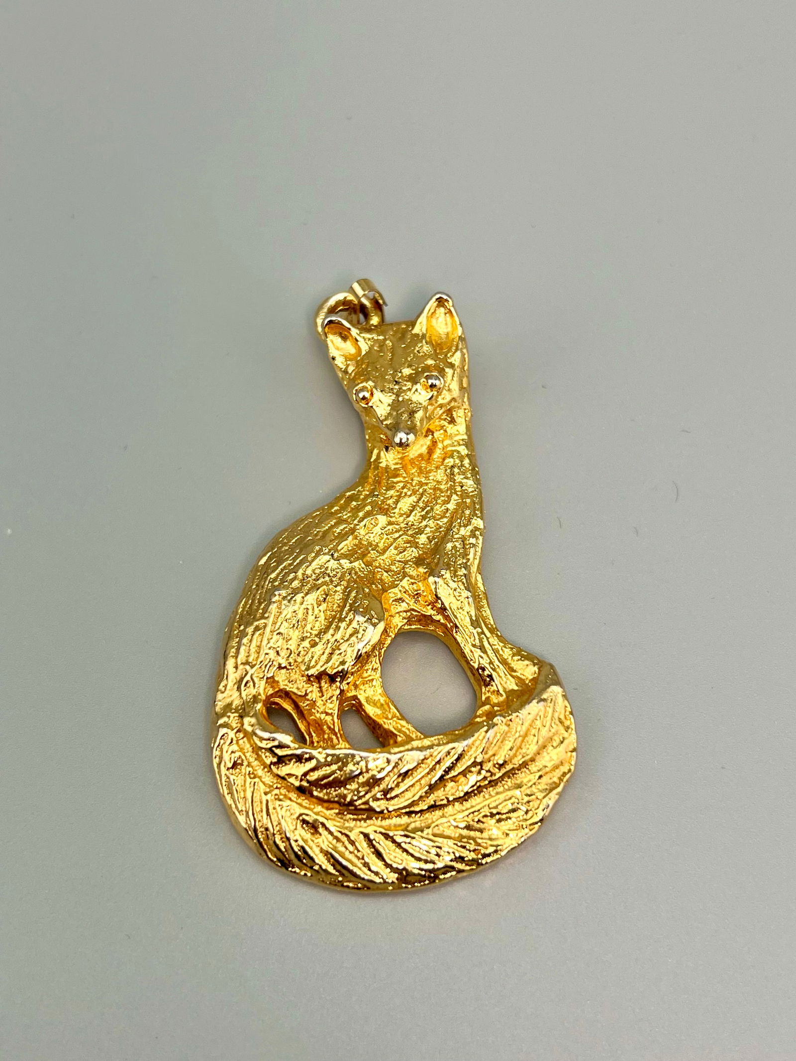 Signed 1973 Mimi di Niscemi Oversize Gold-Tone Fox Pendant: A sculptural vintage pendant by Mimi di N, dated 1973. Designed in a rich gold-tone finish, the piece depicts a seated fox with its tail curled gracefully around the body, capturing both elegance and