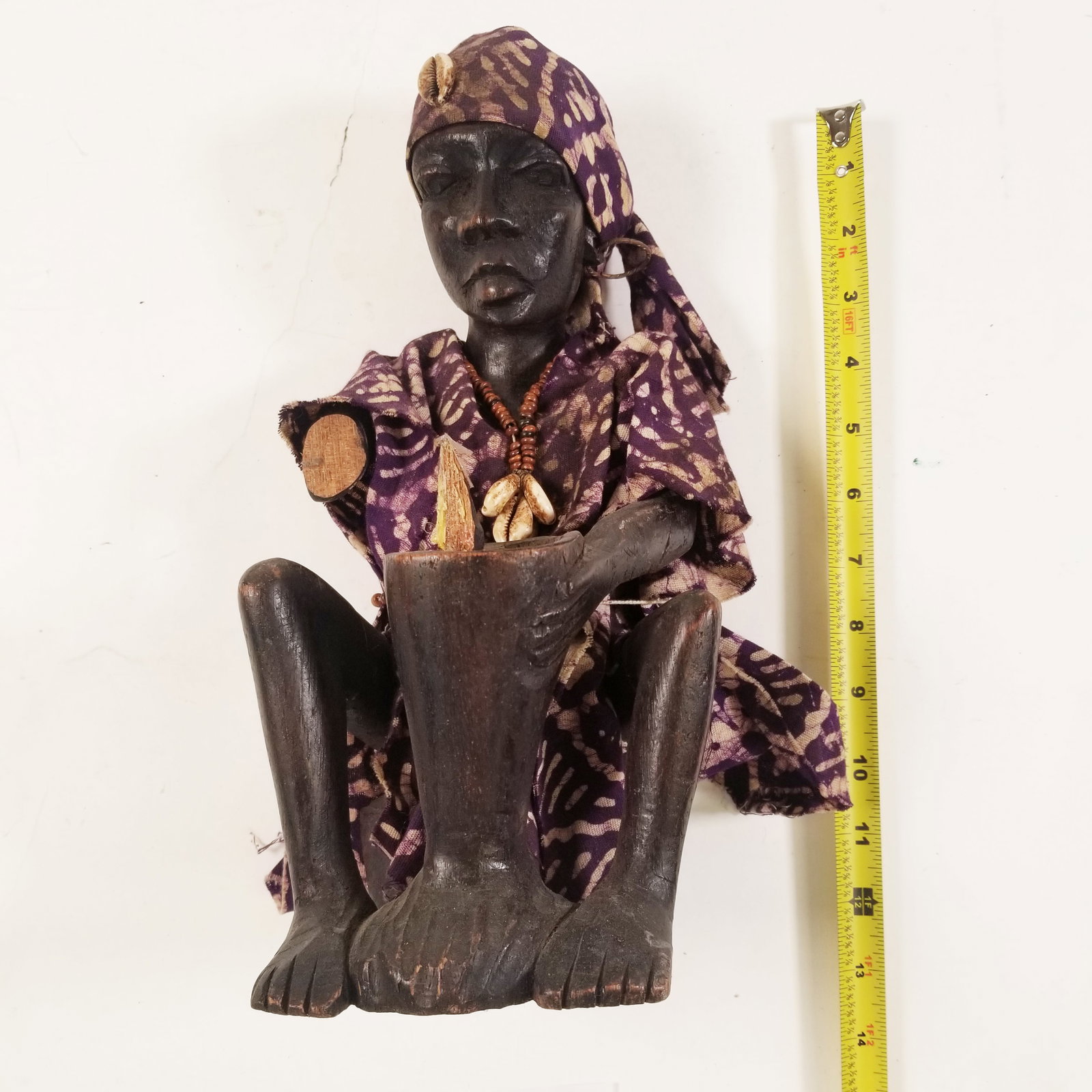 African Wooden Figurine with Mortar & Pestle: A hand-carved wooden figurine depicting a figure dressed in vibrant purple cloth, pounding in a mortar and pestle. Showcasing traditional daily life, it?s a charming piece of African folk art and a un
