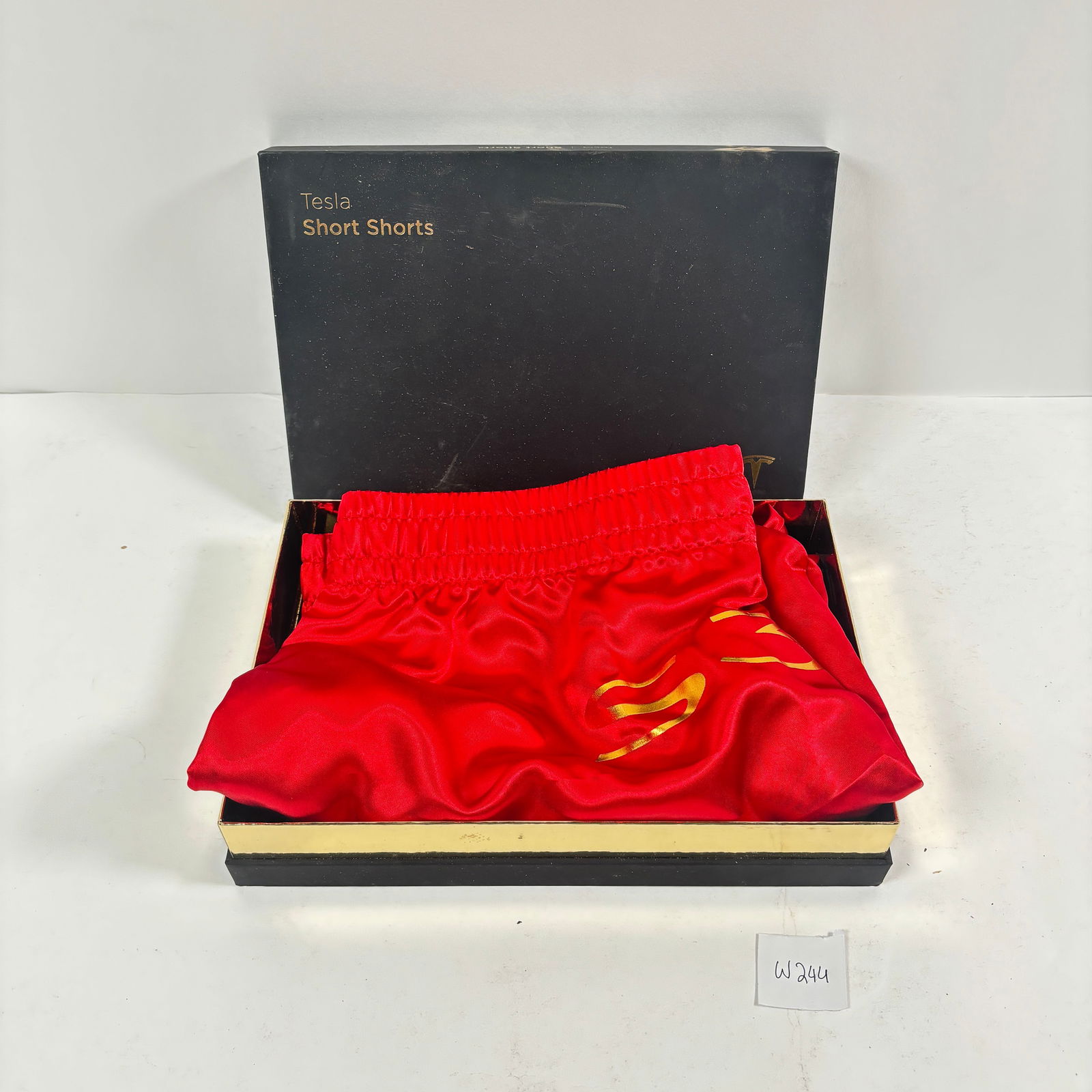 Tesla Short Shorts in Red: Up for sale are a pair of Tesla Short Shorts in a vibrant red color. These shorts feature the word "SEXY" written across the rear in a bold gold lettering. A fun and attention-grabbing piece of novelt