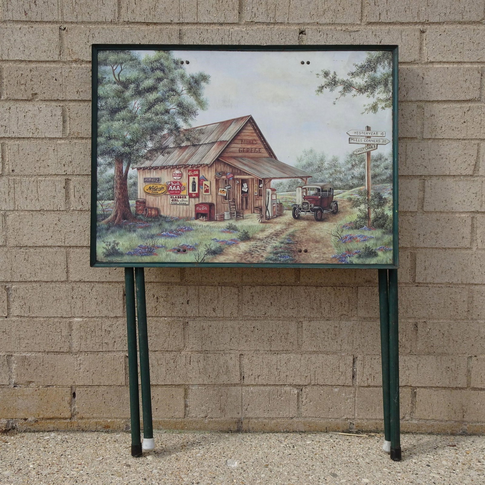 Mike's Garage Coke Folding Table Kay Lamb Shannon: A vintage-style folding table featuring a playful "Mike's Garage" motif alongside classic Coke branding and signatures from artists Kay Lamb and Shannon. This decorative and functional piece is perfec