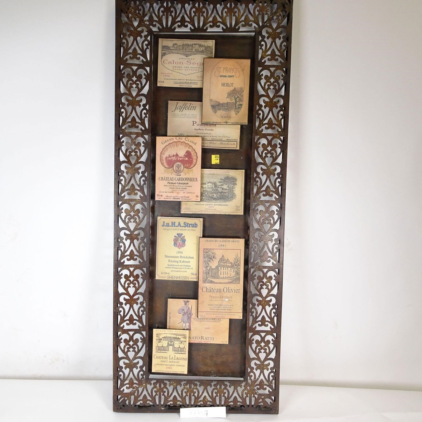 Vintage Wine Label Wall Art: Decorative vintage-style wall art featuring a curated collage of classic wine labels from France, Germany, Italy, and the USA, displayed behind glass in an ornate, openwork metal frame.A perfect state