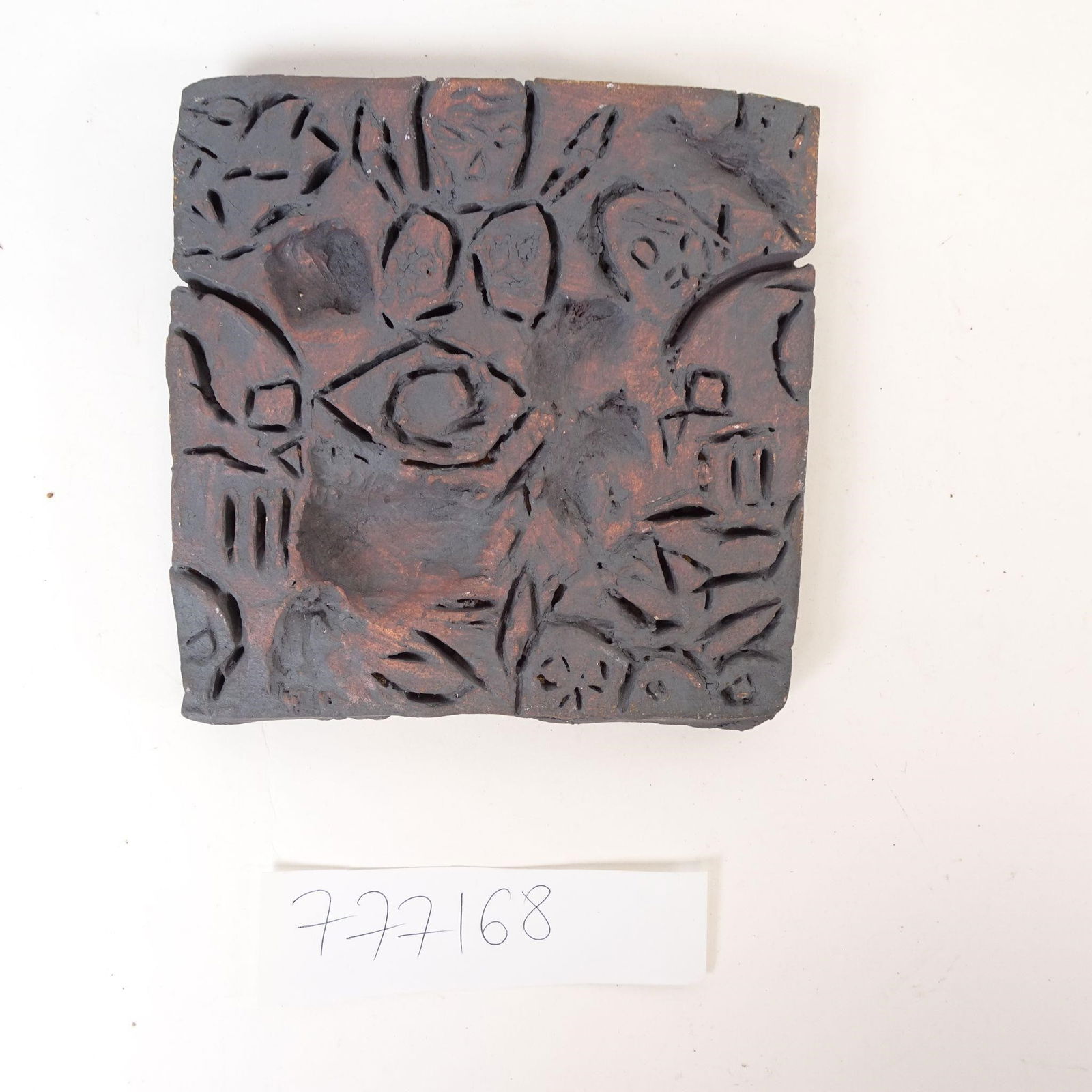 Handcrafted Ceramic Relief Tile: Offered for sale is a handcrafted ceramic relief tile featuring a symbolic abstract design. The composition centers around a stylized eye motif, surrounded by carved decorative and geometric elements.