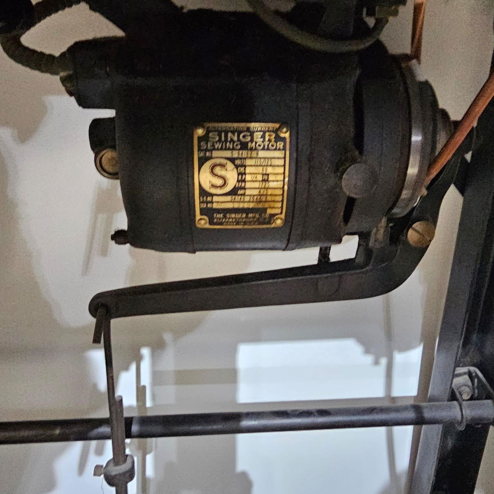 Antique Singer Sewing Machine: Original vintage Singer sewing machine mounted in a solid wooden industrial table with cast metal base and foot pedal. Equipped with an original Singer electric motor, belt-driven mechanism, and an ad