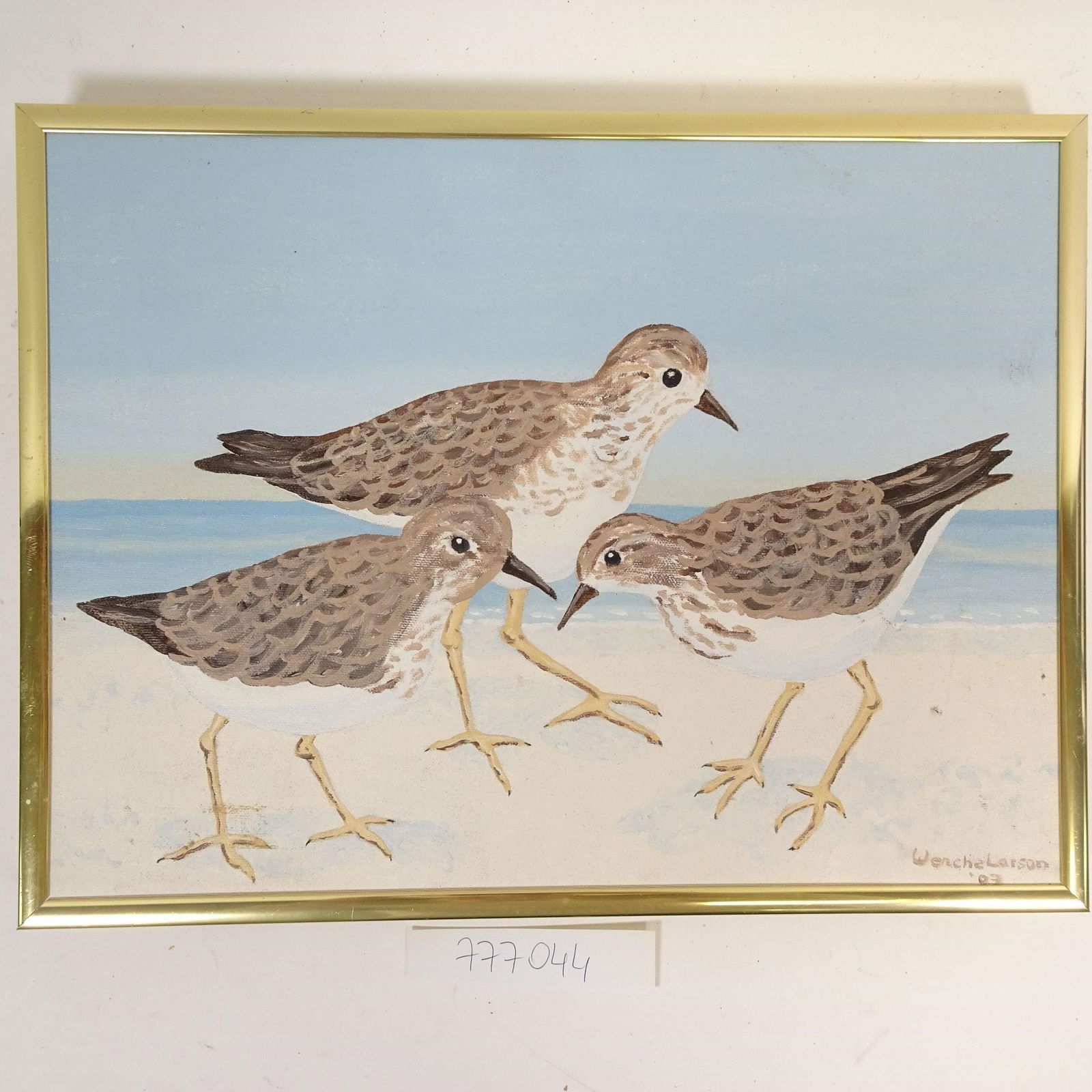 Wenche Larson (2002) - Shorebirds by the Sea: Original hand-painted artwork on canvas depicting three shorebirds standing along a sandy beach with the sea in the background. The painting features soft, natural tones of blue, beige, and brown, cre