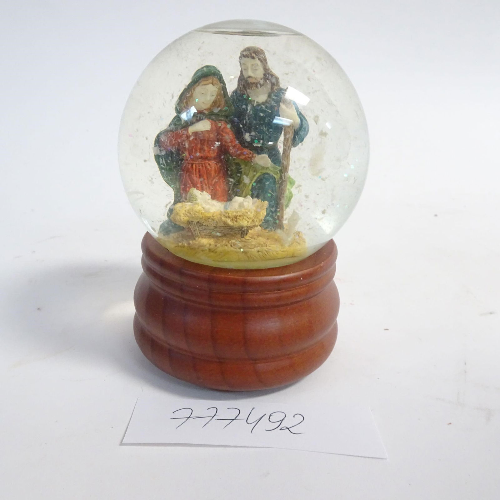 Nativity Snow Globe Music Box: Decorative nativity-themed snow globe music box featuring the Holy Family at the manger. The glass globe is set on a wooden base with a classic finish. The wind-up mechanism plays "Little Town of Beth