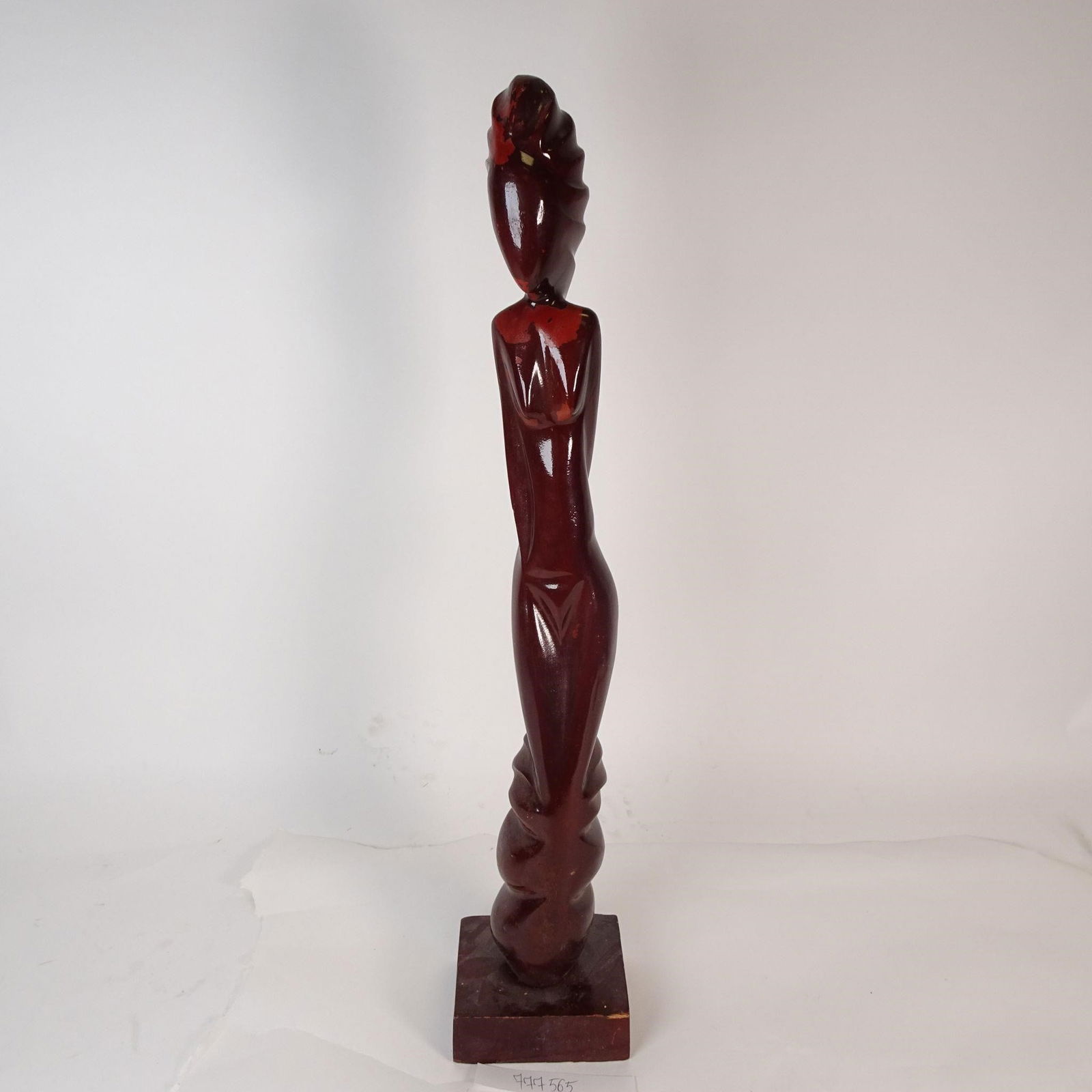 Tall Hand-Carved Abstract Wooden Sculpture: This auction features a tall, hand-carved wooden sculpture with an abstract, elongated human form. The piece is finished in a deep reddish-brown tone with visible areas of natural wear, adding charact