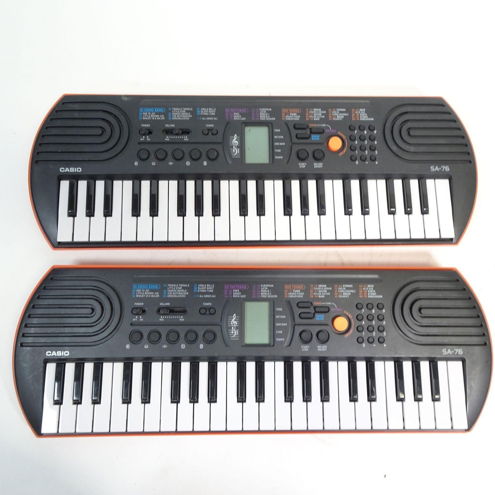 Lot of 2 Casio SA-76 Keyboards: Lot includes two identical Casio SA-76 educational keyboards, both in orange color. The SA-76 is a well-known beginner keyboard designed for kids and entry-level players. Lightweight and portable, fea