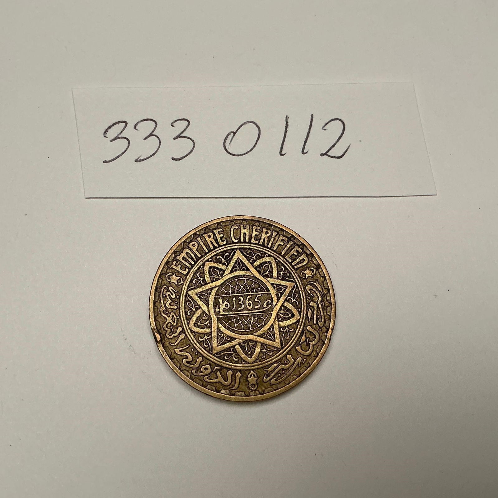 Maroko - 5 Francs 1365 AH (1945): Maroko - 5 Francs 1365 AH (1945)Vintage 1945 Morocco 5 Francs coin (Empire Cherifien), bronze-aluminum composition with beautiful Arabic script and star design. A collectible coin from the French Prot