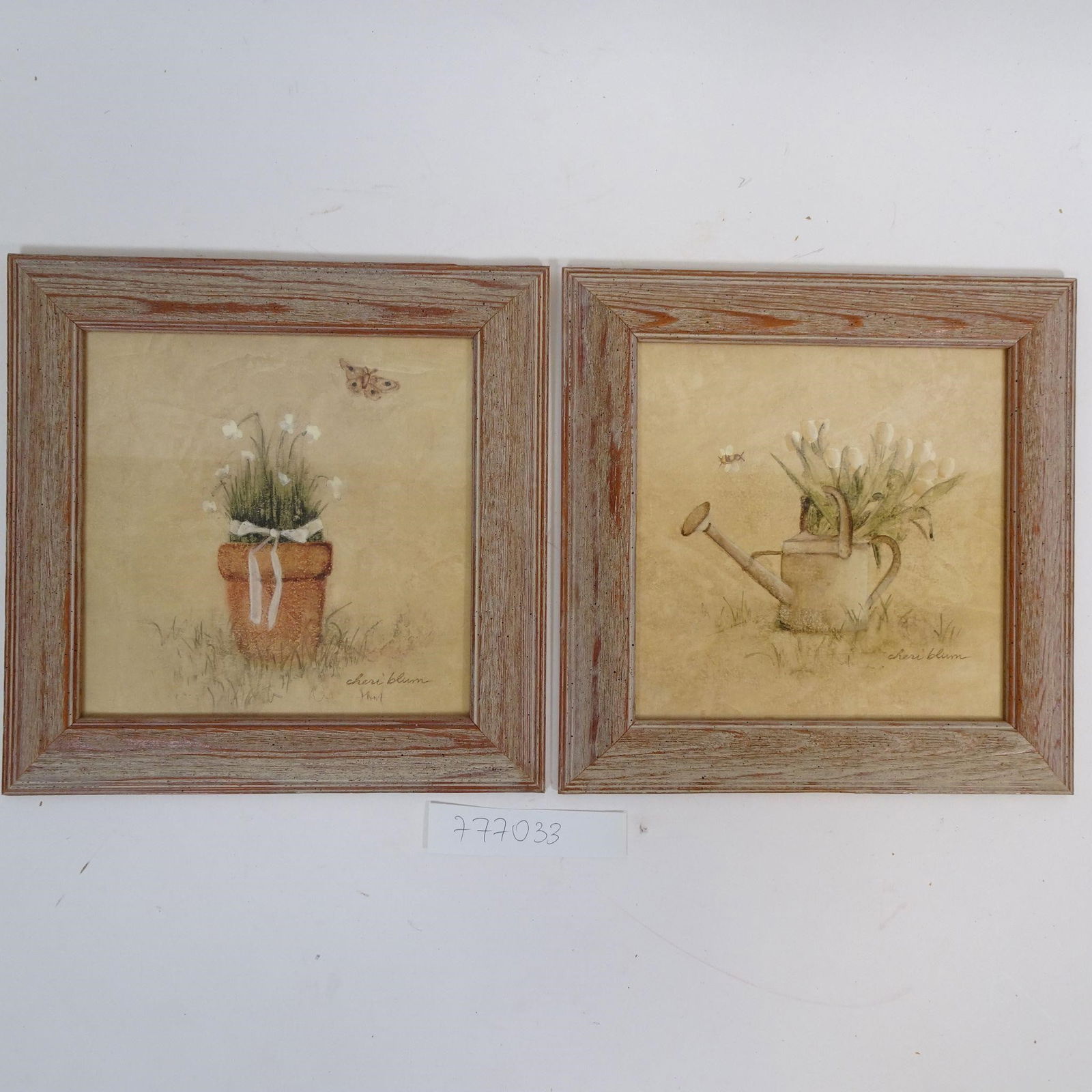 Set of 2 Vintage Floral Prints in Wooden Frames: Charming set of two vintage floral and garden-themed artworks featuring a flower pot and a watering can with blooms. Soft pastel tones combined with rustic, distressed wooden frames create a warm cott
