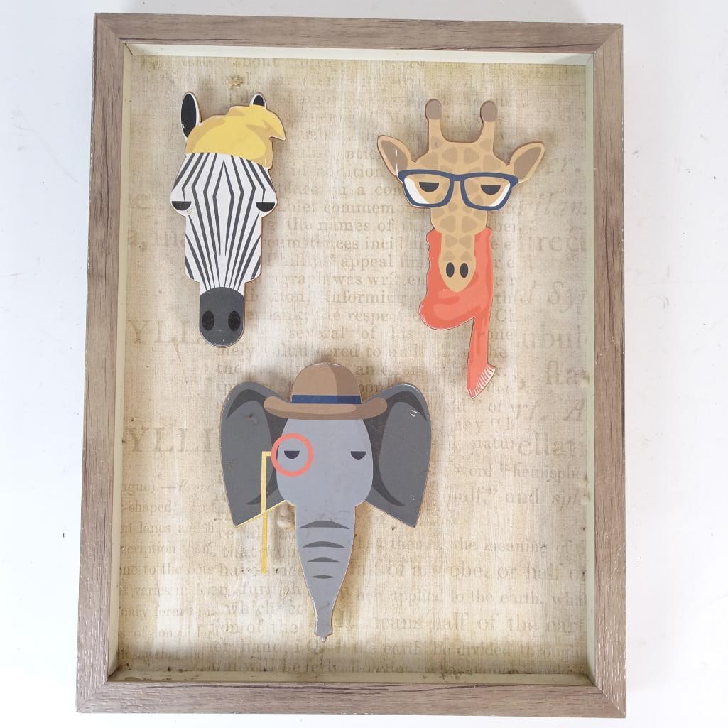 Safari Animals Framed Wall Art: Decorative framed wall art featuring a playful safari animal theme with a zebra, giraffe, and elephant illustrated in a modern, whimsical style. The artwork is mounted within a wood-tone frame and pro