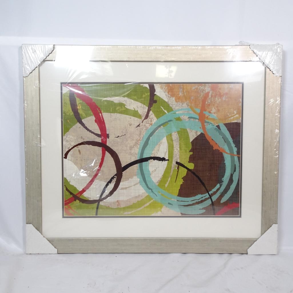Large Framed Abstract Wall Art: Large contemporary abstract wall art featuring bold circular brush strokes and layered textures in green, turquoise, red, brown, and neutral tones. The artwork is professionally framed in a light silv