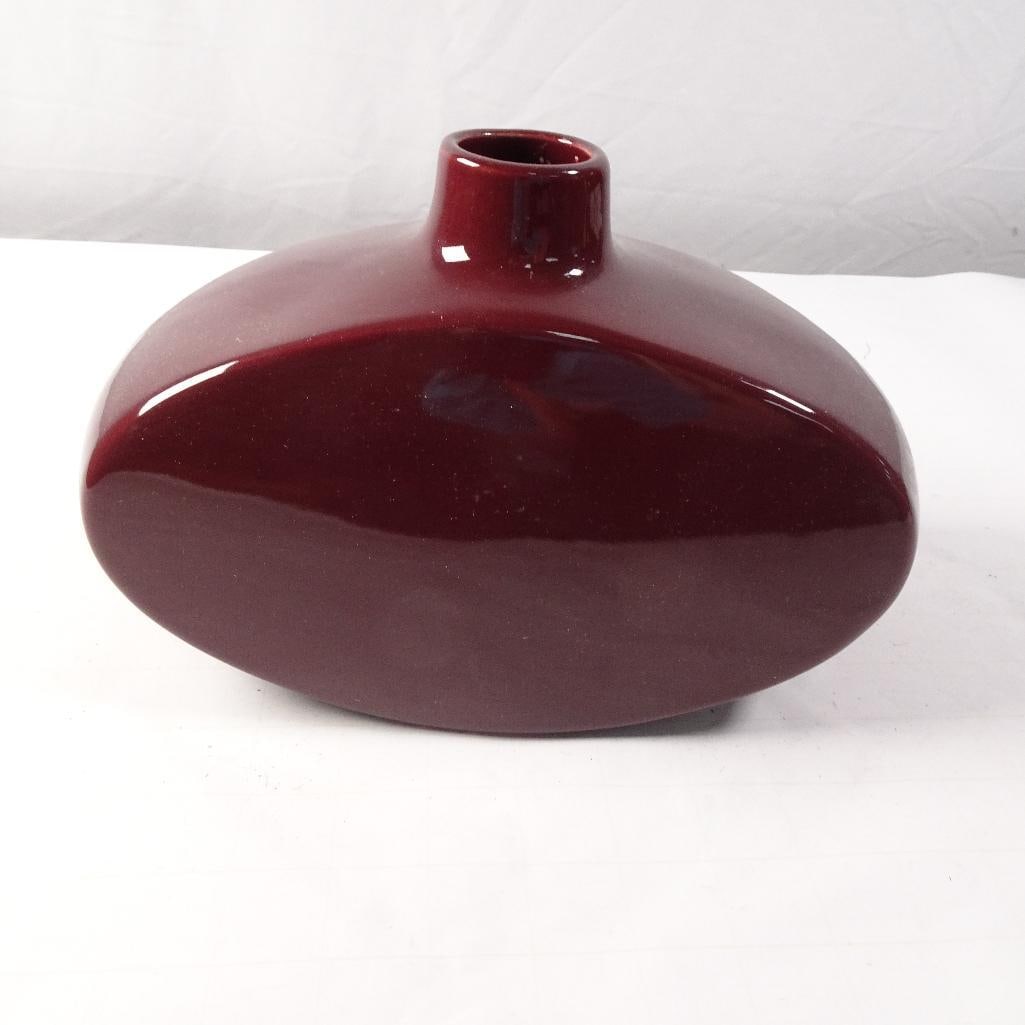 Contemporary Burgundy Art Glass Bud Vase: Elegant contemporary art glass vase featuring a rich burgundy color with a glossy finish and a modern, sculptural silhouette. The low-profile oval body and narrow neck make it ideal as a bud vase or d