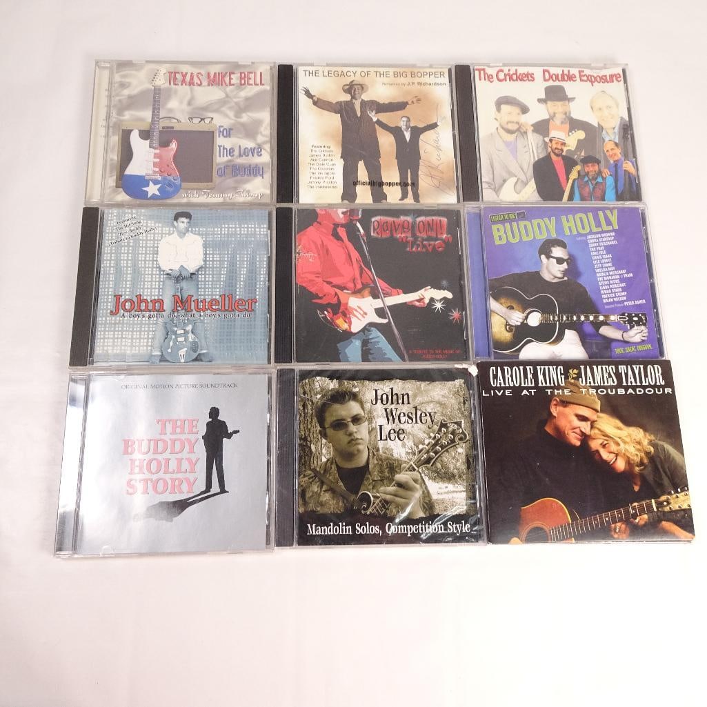 Lot of 9 CDs: Pre-owned lot of 9 music CDs featuring Buddy Holly tributes, rock and roll classics, bluegrass, country, and singer-songwriter favorites. Sold as one lot.
