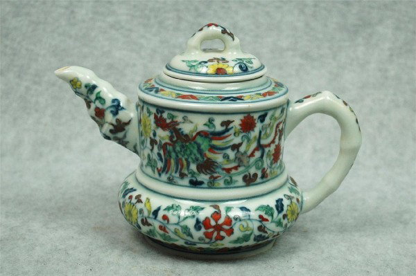 Chinese Dou-Cai Porcelain Teapot: Chinese doucai porcelain teapot, the cylindrical upper section painted in underglaze blue and bright enamels with phoenix amid flowering leafy tendrils repeated on the compressed globular lower sectio