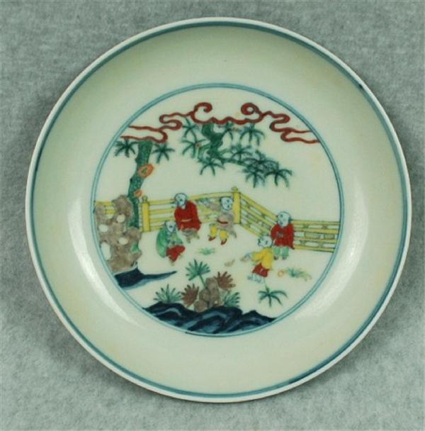 Chinese Dou-Ccai Porcelain Plate: Chinese doucai porcelain plate, the interior well decorated in underglaze blue and bright enamels with children playing on a garden terrace, all within double cobalt blue rings repeated on the rim, th