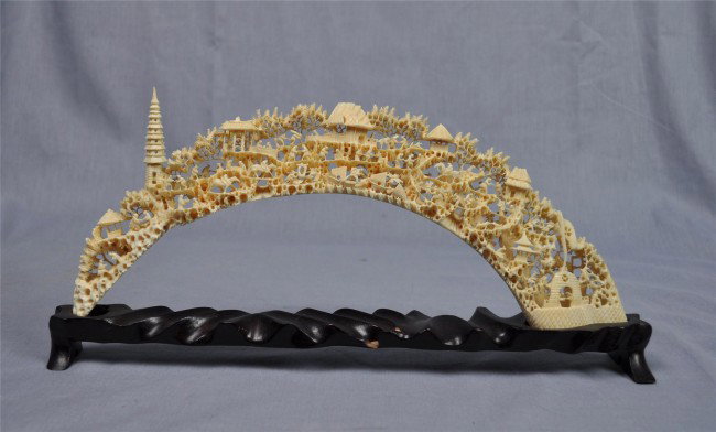Chinese tinted ivory tusk: Chinese tinted ivory tusk 20th century, elaborately carved and pierced with an animated scene of miniature figures traversing through a dense landscape scattered with pavilions, pagodas and villas; to