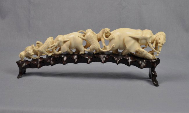 Chinese ivory figural carving: Chinese ivory figural carving, 20th century, the tapering tusk carved and pierced as two large elephants attempting to repel a fierce attack by multiple lions and tigers, the animals finely rendered i