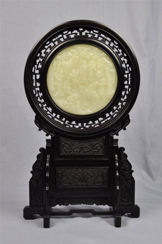 Chinese wood table screen with a jade plaque: Chinese wood table screen with a jade plaque, the translucent pale green circular plaque carved with figures in a landscape, reversed by a wood plaque carved with a long poetic textual passage within 