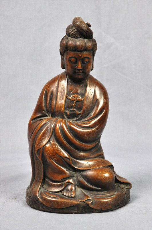 Chinese bronze figure of Guanyin with silver inla: Chinese patinated bronze figure of Guanyin with silver inlaid accents, the Buddhist deity seated in a pose of royal ease with the hand clasped together below the folds of the long robes with silver-in