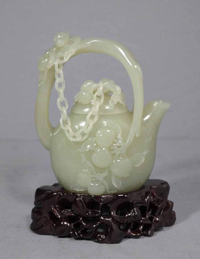 Well Carved Chinese He-Tian Jade Teapot: Well carved Chinese he-tian jade teapot, decorated with a monkey hanging on the handle. Good condition. 7.25" height included carved wood stand.