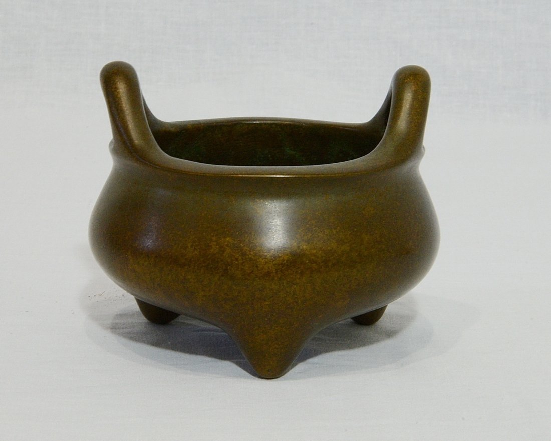 Chinese Bronze Tripod Incense Burner With Mark: Chinese bronze tripod incense burner, decorated with two handles on the top. Four relief character mark on the base. Good condition. 4.75" diam x 2.75" height.