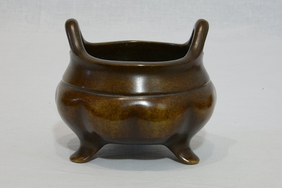 Chinese Bronze Tripod Incense Burner With Mark: Chinese bronze tripod incense burner with handles. Four character relief mark on the base. Good condition. 4.75" diam x 3" height.