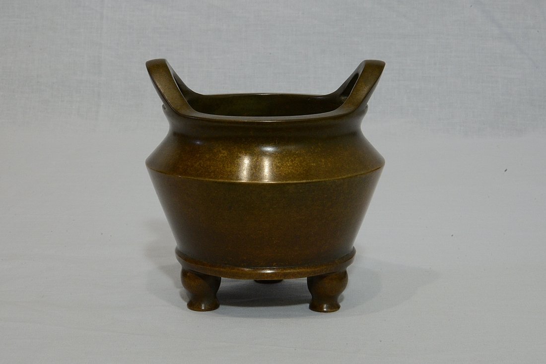 Chinese Bronze Tripod Incense Burner With Mark: Chinese bronze tripod incense burner with handles. Six character relief mark on the base. Good condition. 4.5" diam x 3.75" height.