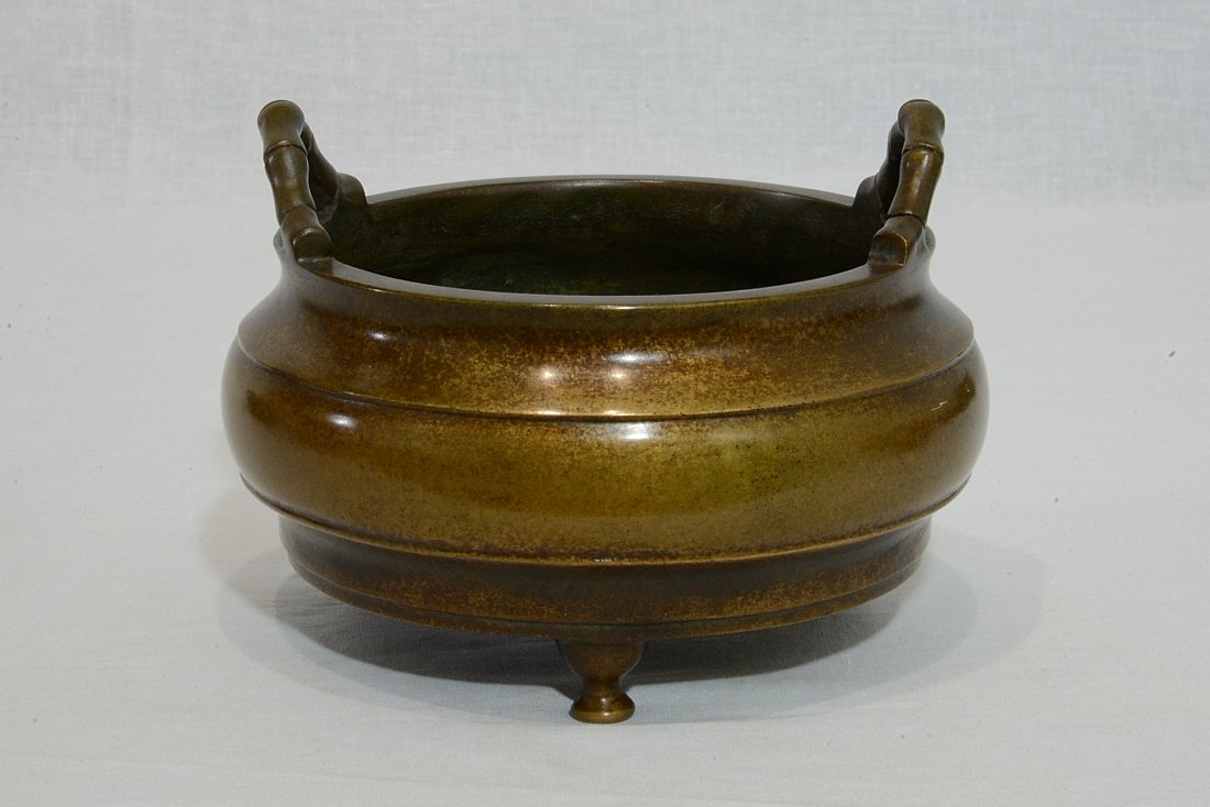 Chinese Bronze Tripod Incense Burner With Mark: Chinese bronze tripod incense burner with two bamboo form handles. Four character relief studio mark. Good condition. 6" wide x 3.25" height.